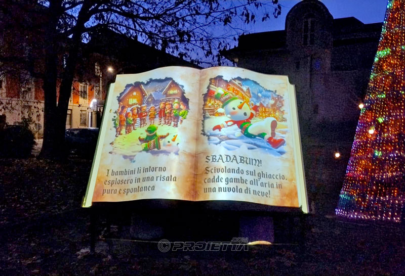 Proiezione di una storia di Natale su un grande libro installato in esterno.